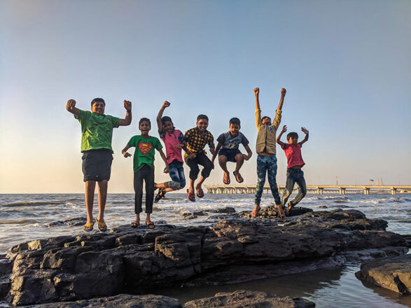 Kids jumping on a rock formation in the water