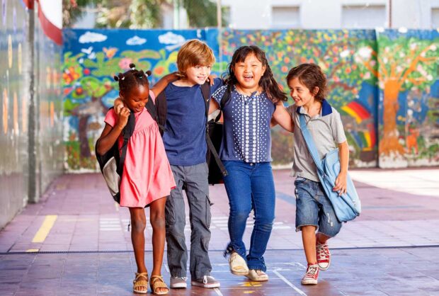 Children in front of a color painted scene with their arms around each other